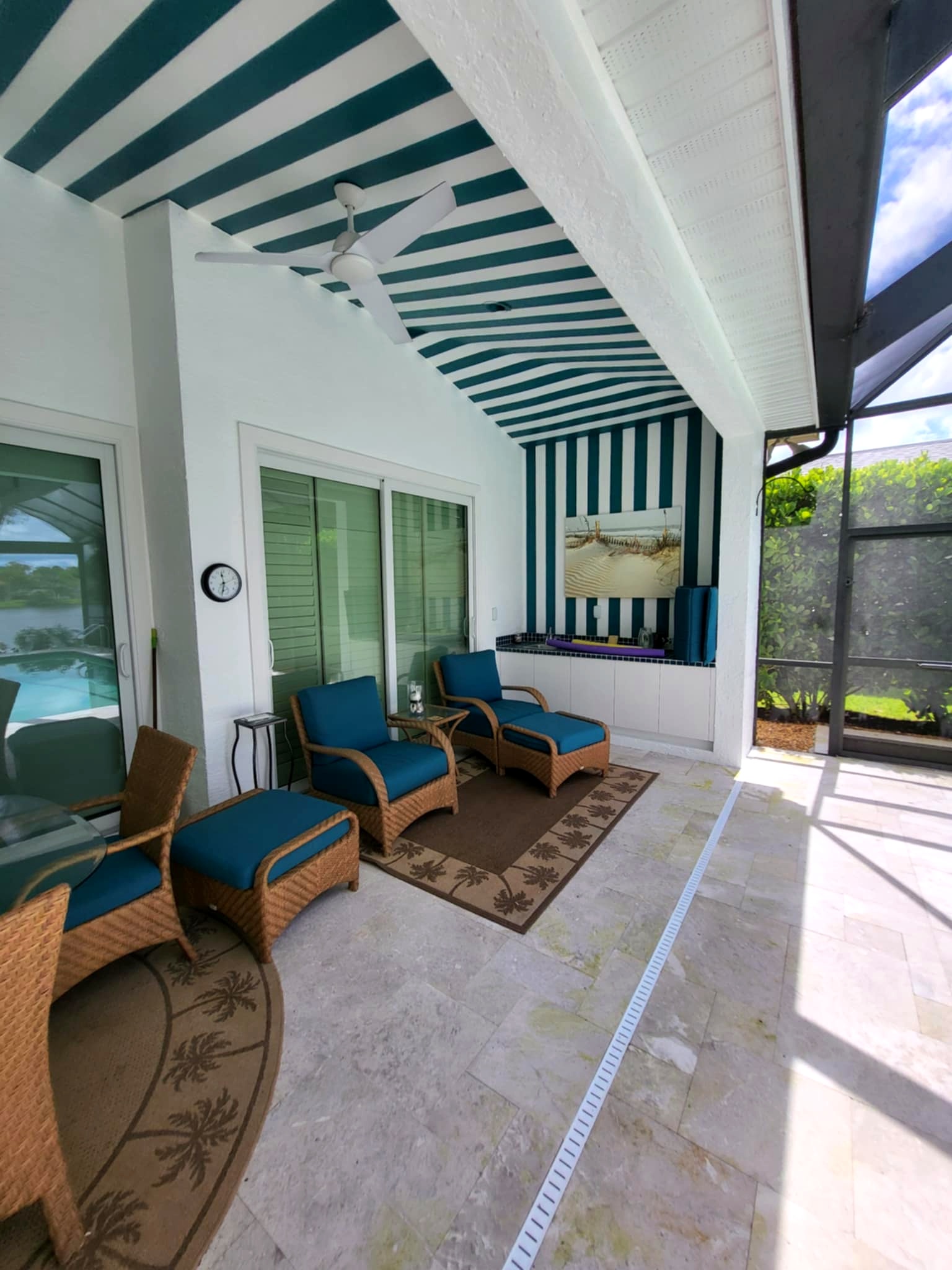Luxury outdoor patio with striped ceiling and wicker lounge furniture after custom exterior painting in Naples, Florida